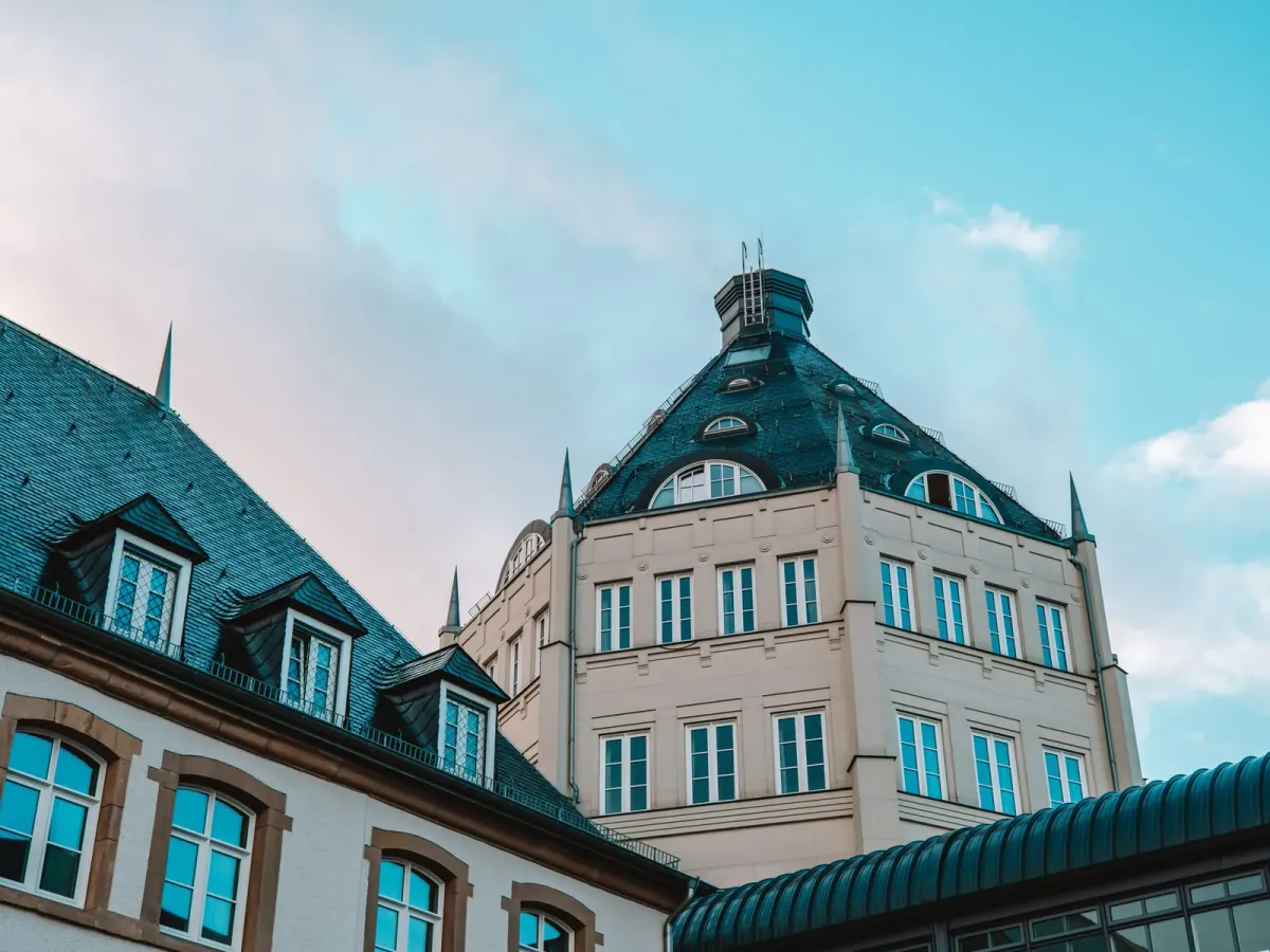 Bâtiment aux toits d’ardoise et sa tour à lucarnes, sous un ciel bleu