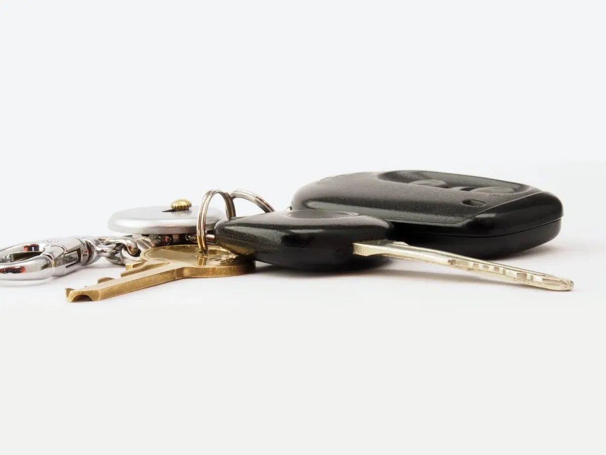 Un trousseau avec une clé de voiture et deux clés plates, posé sur un fond blanc