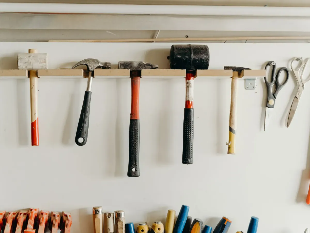 Hammers and scissors hanging in a neat row on a workshop wall