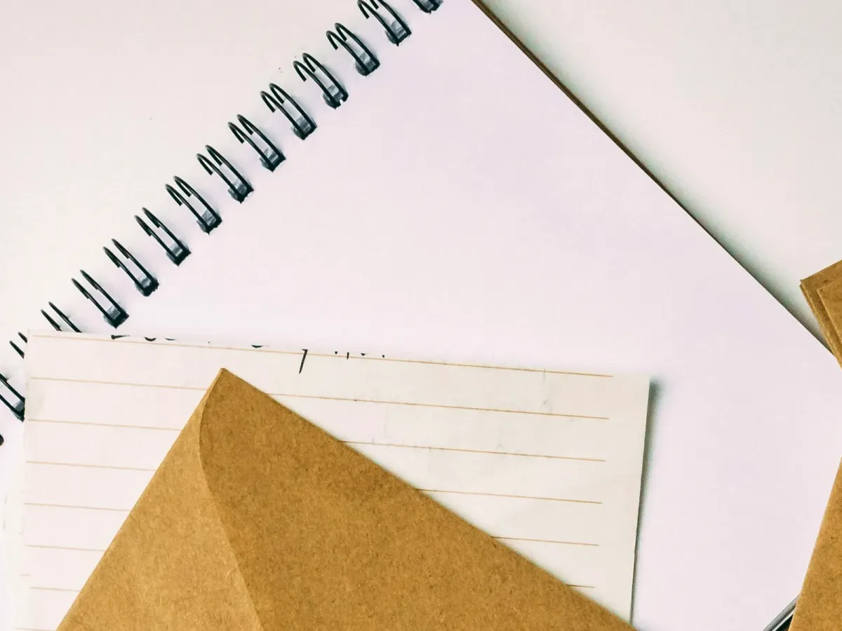 Enveloppe kraft posée sur des carnets ouverts aux pages vierges