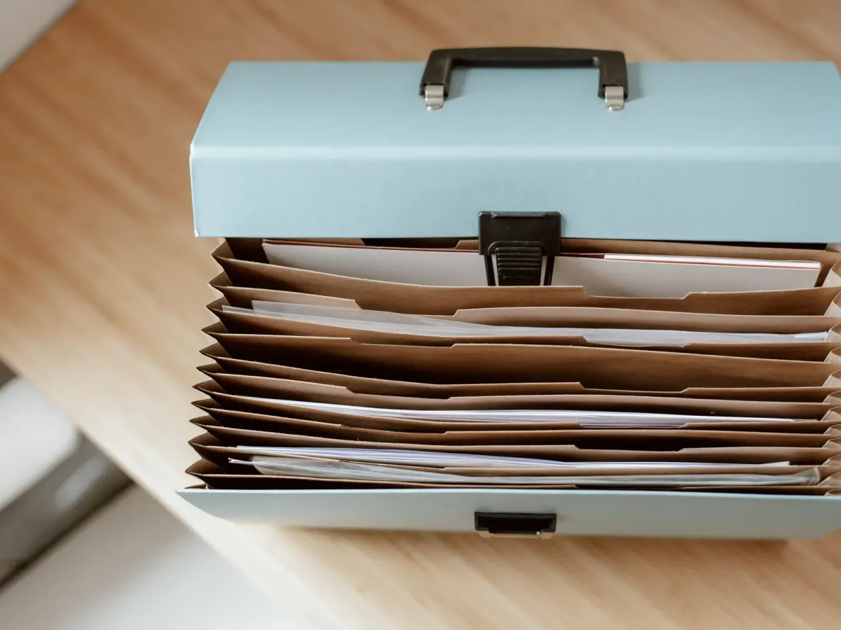 Trieur à soufflets rempli de documents, posé sur un bureau en bois clair