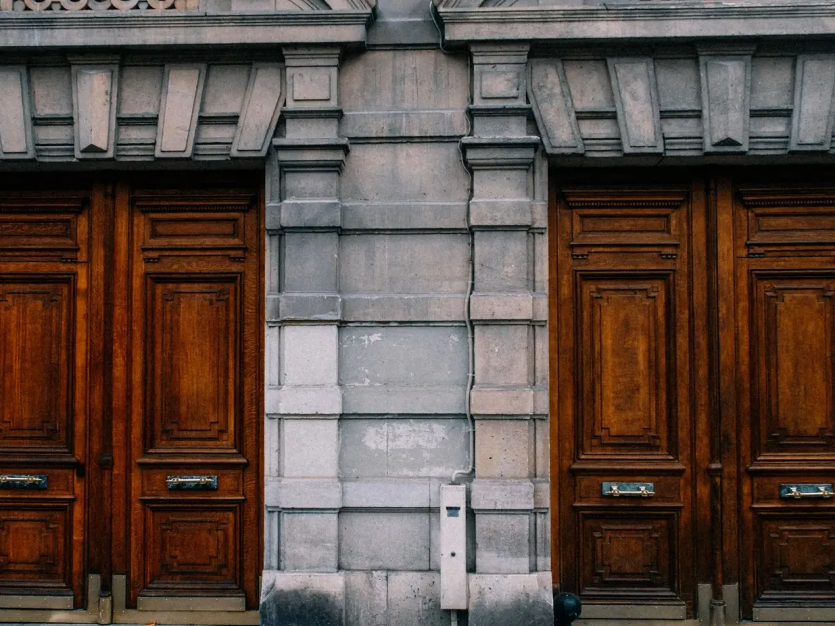 Two carved wooden doors in the stone facade of a classic city building