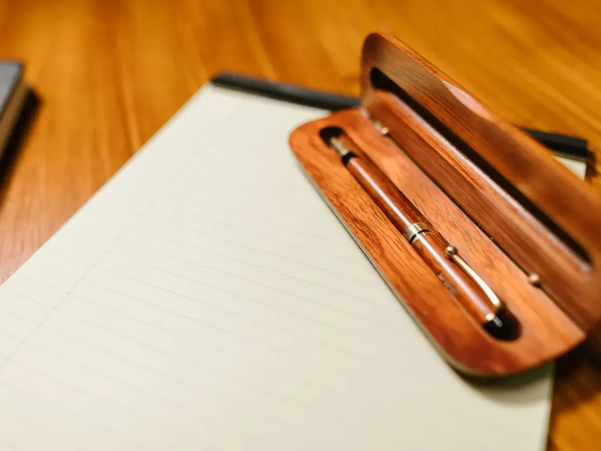 Stylo dans un étui en bois posé sur un bloc-notes, sur un bureau
