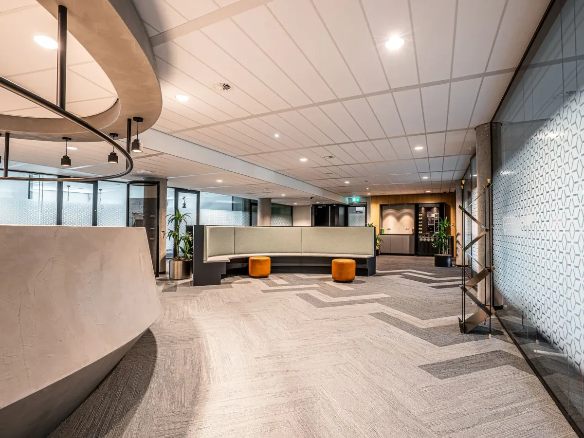 Espace d’accueil lumineux d’un immeuble de bureaux, avec un comptoir courbe et une banquette