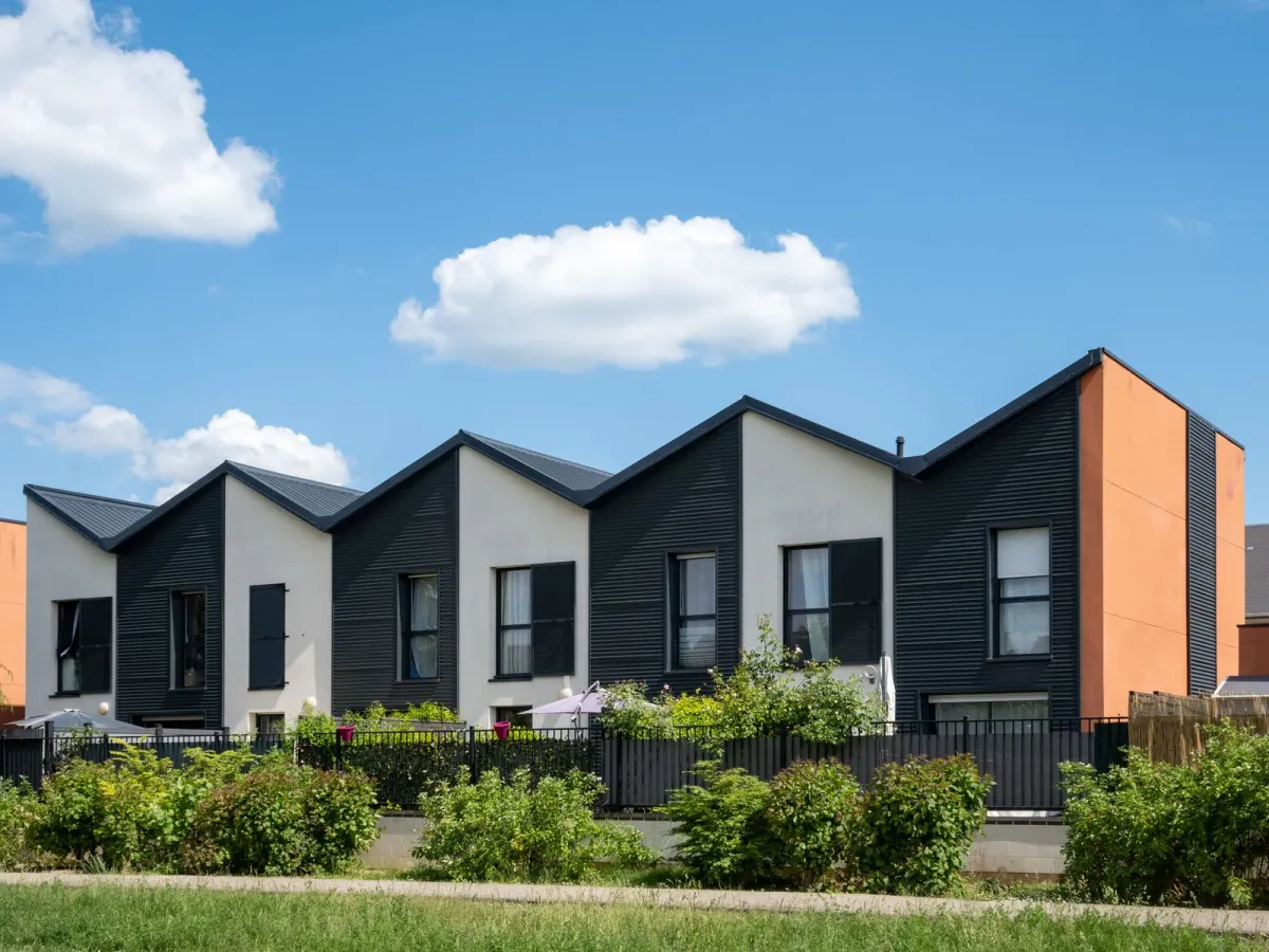 Rangée de maisons modernes aux pignons noirs et blancs, derrière une haie