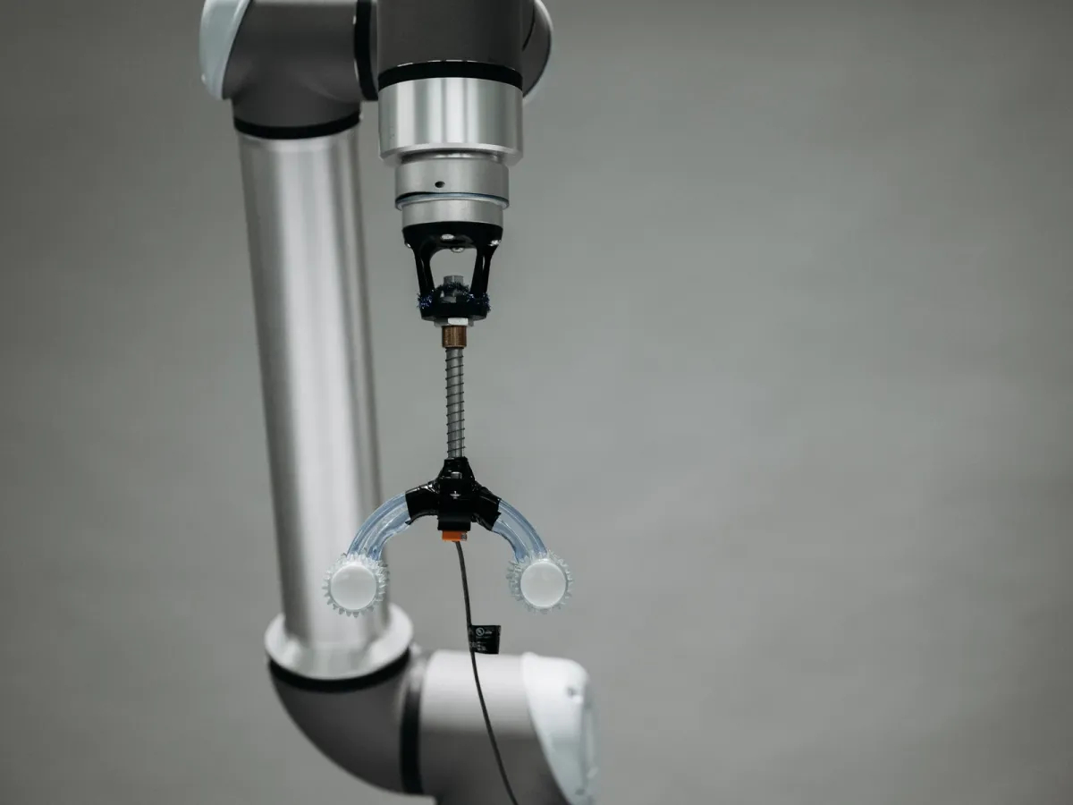 Bras robotisé muni d’une pince, sur un fond gris uni