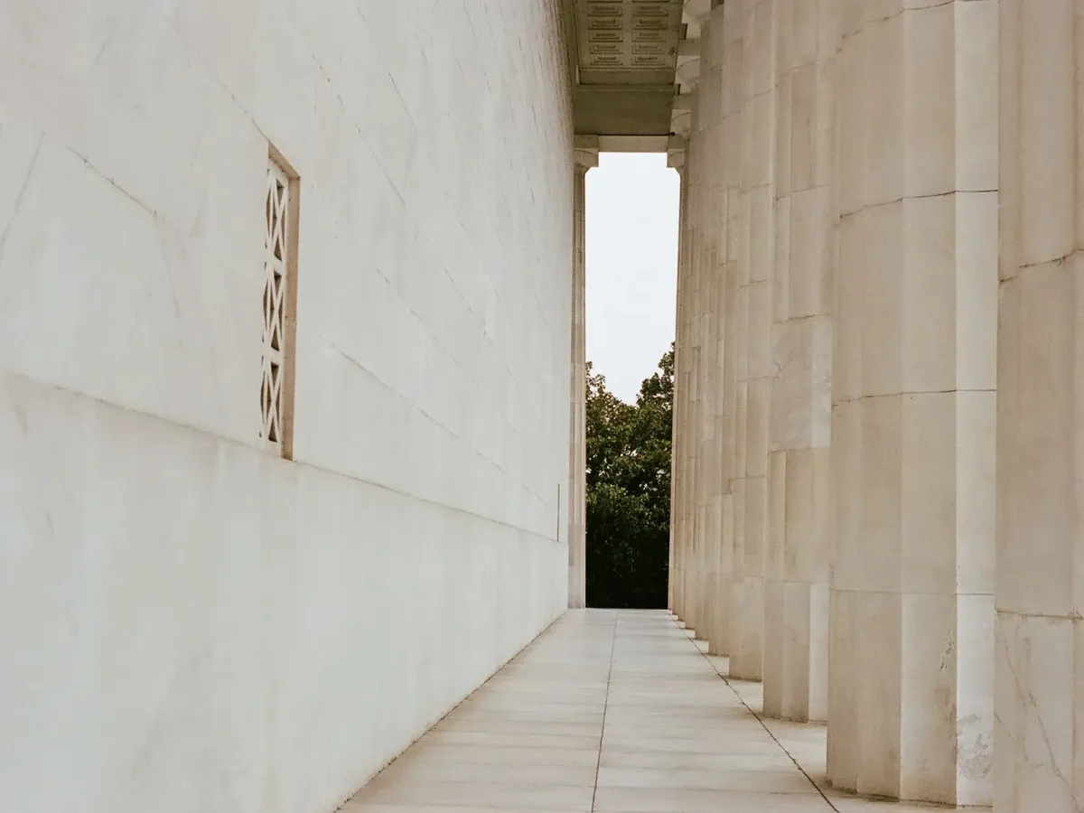 Colonnade de marbre blanc le long d’un mur, dans une lumière douce