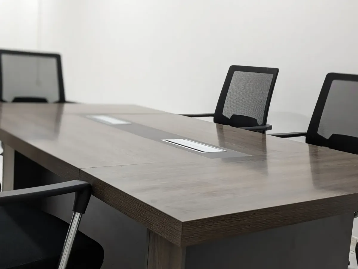 An empty conference table with black chairs in a bright office