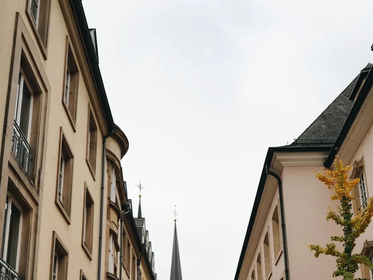 Rue de la vieille ville de Luxembourg bordée de façades claires, avec deux flèches au fond