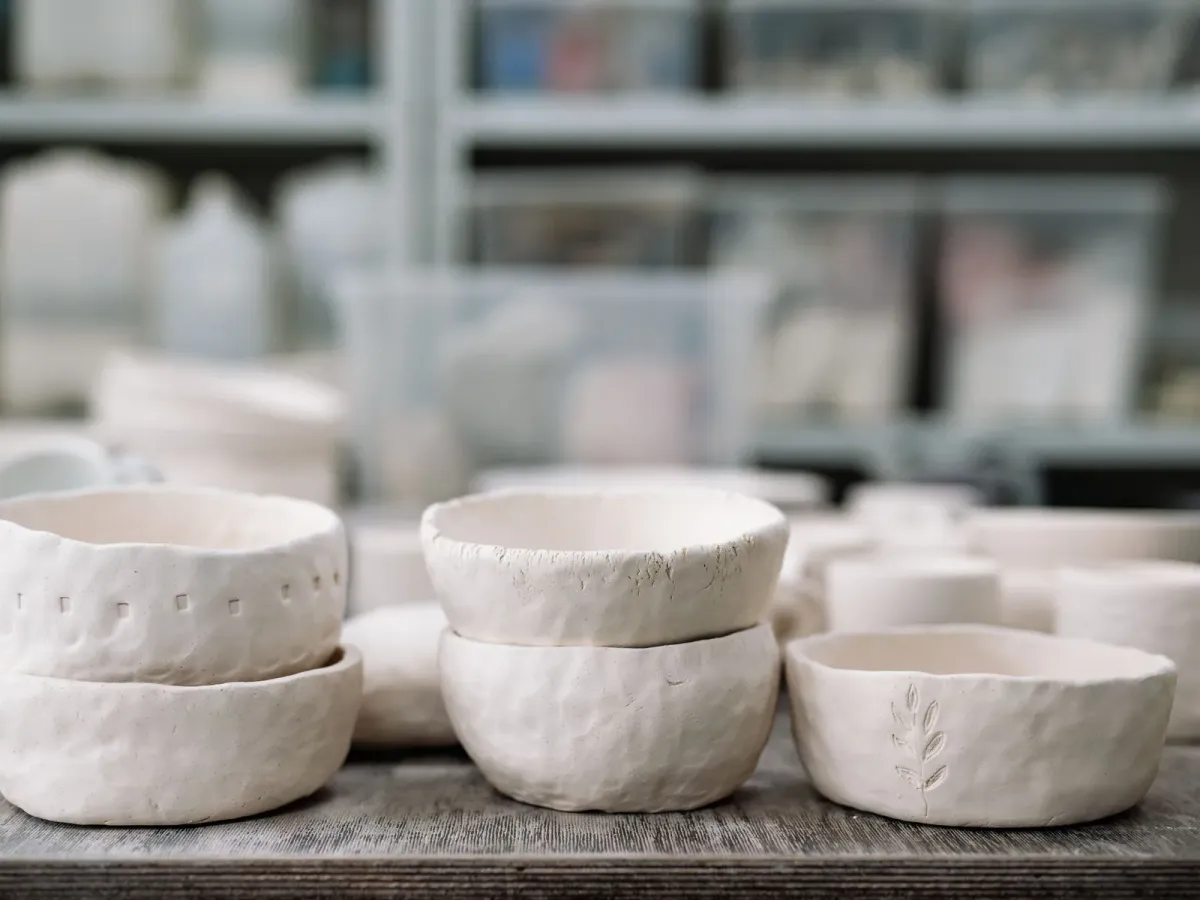 Handmade white clay bowls on a wooden table in a pottery studio