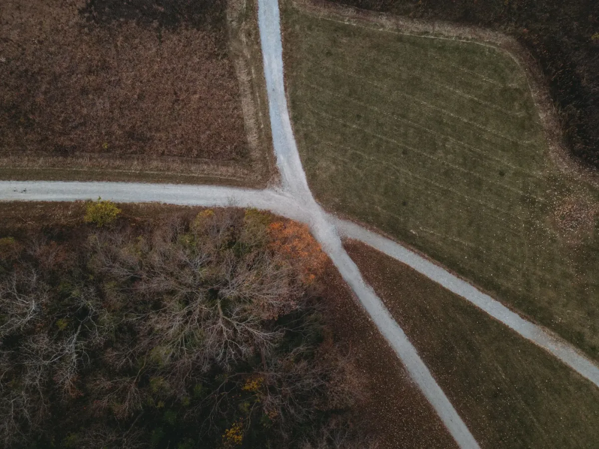 Vue aérienne d’un chemin rural qui se divise en deux entre des champs d’automne