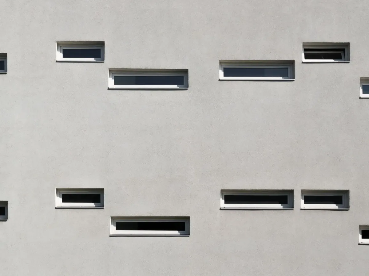 A light grey facade with narrow horizontal windows at staggered heights
