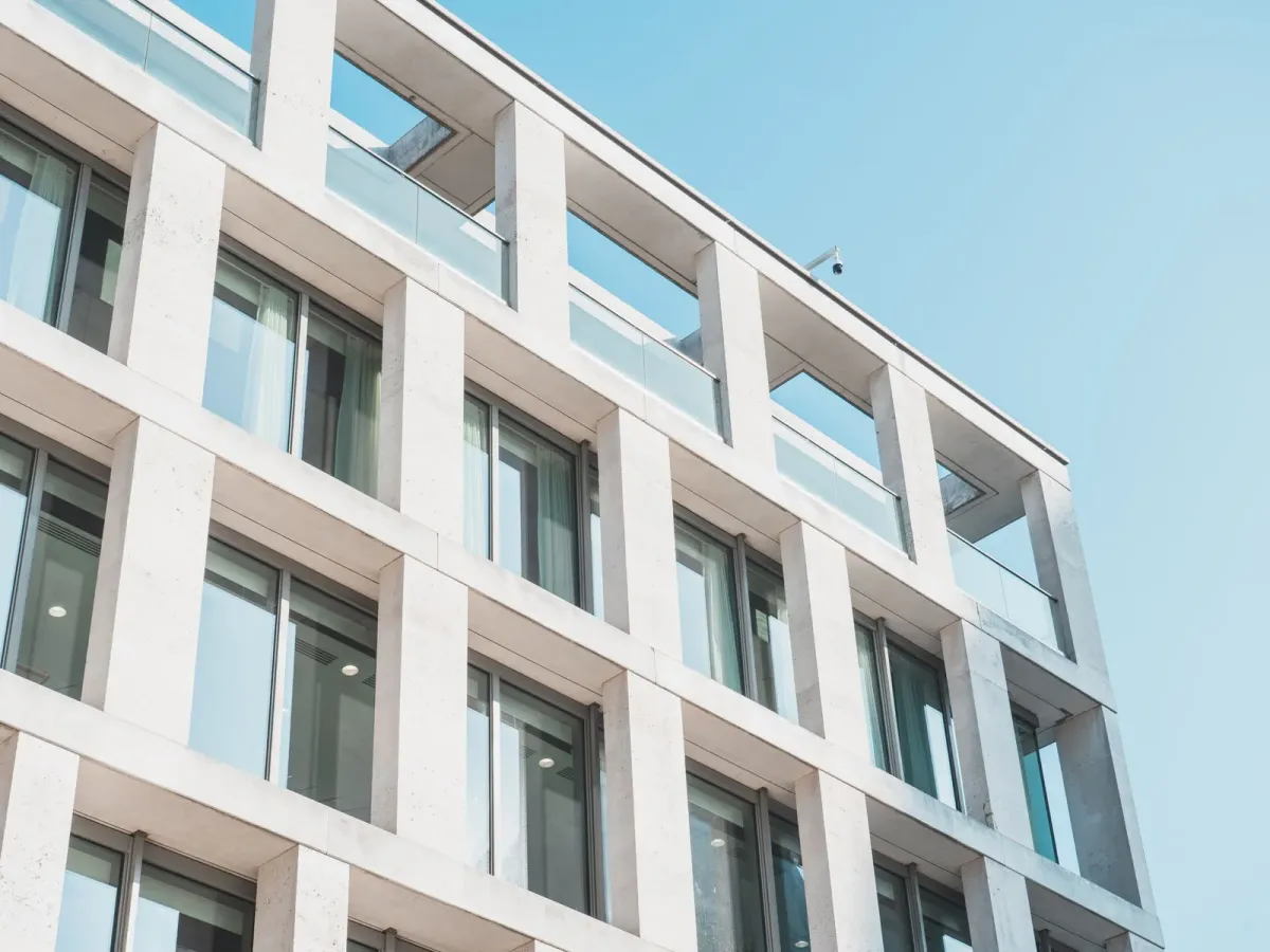 Façade blanche aux fenêtres en retrait, sous un ciel clair