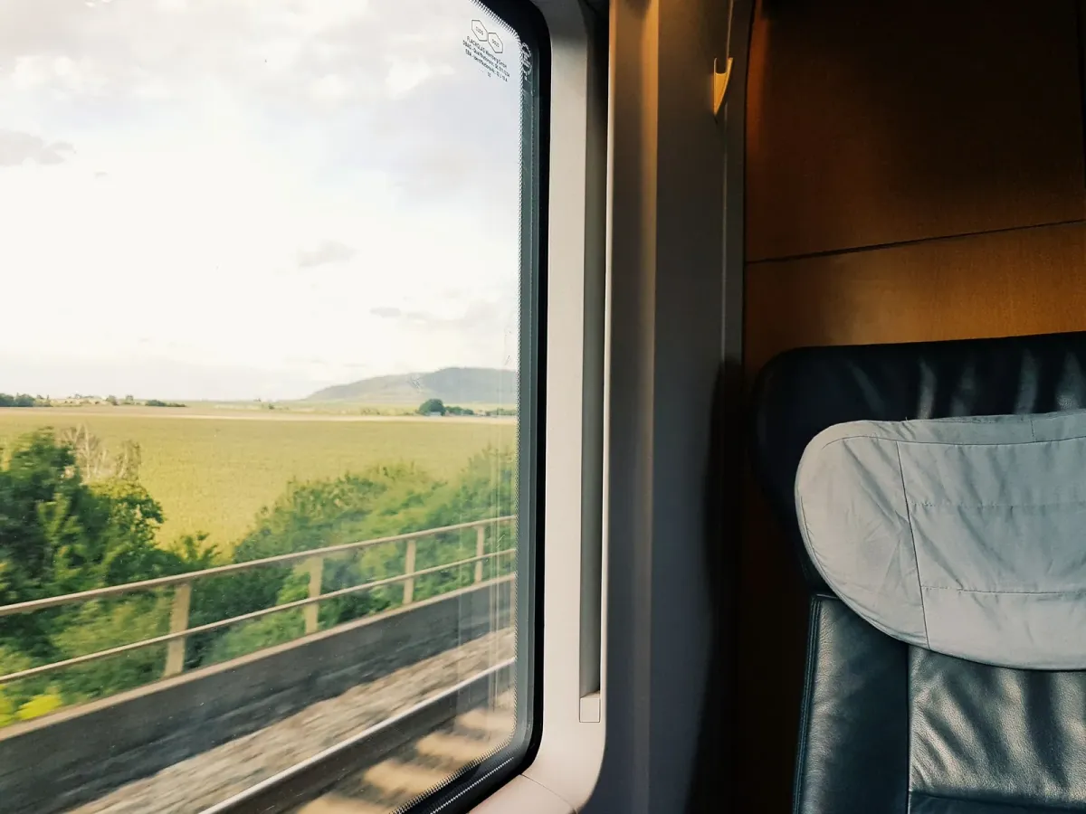 Siège de train près d’une fenêtre ouverte sur des champs et des arbres