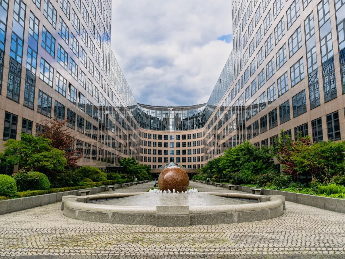 A courtyard between curved office buildings, with a stone sphere fountain at its centre