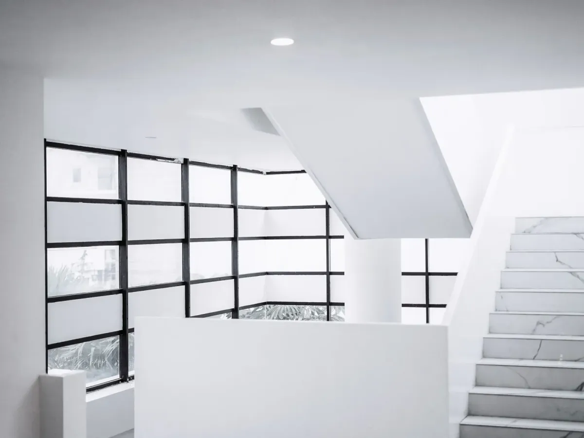 A white staircase with marble steps beside black-framed windows